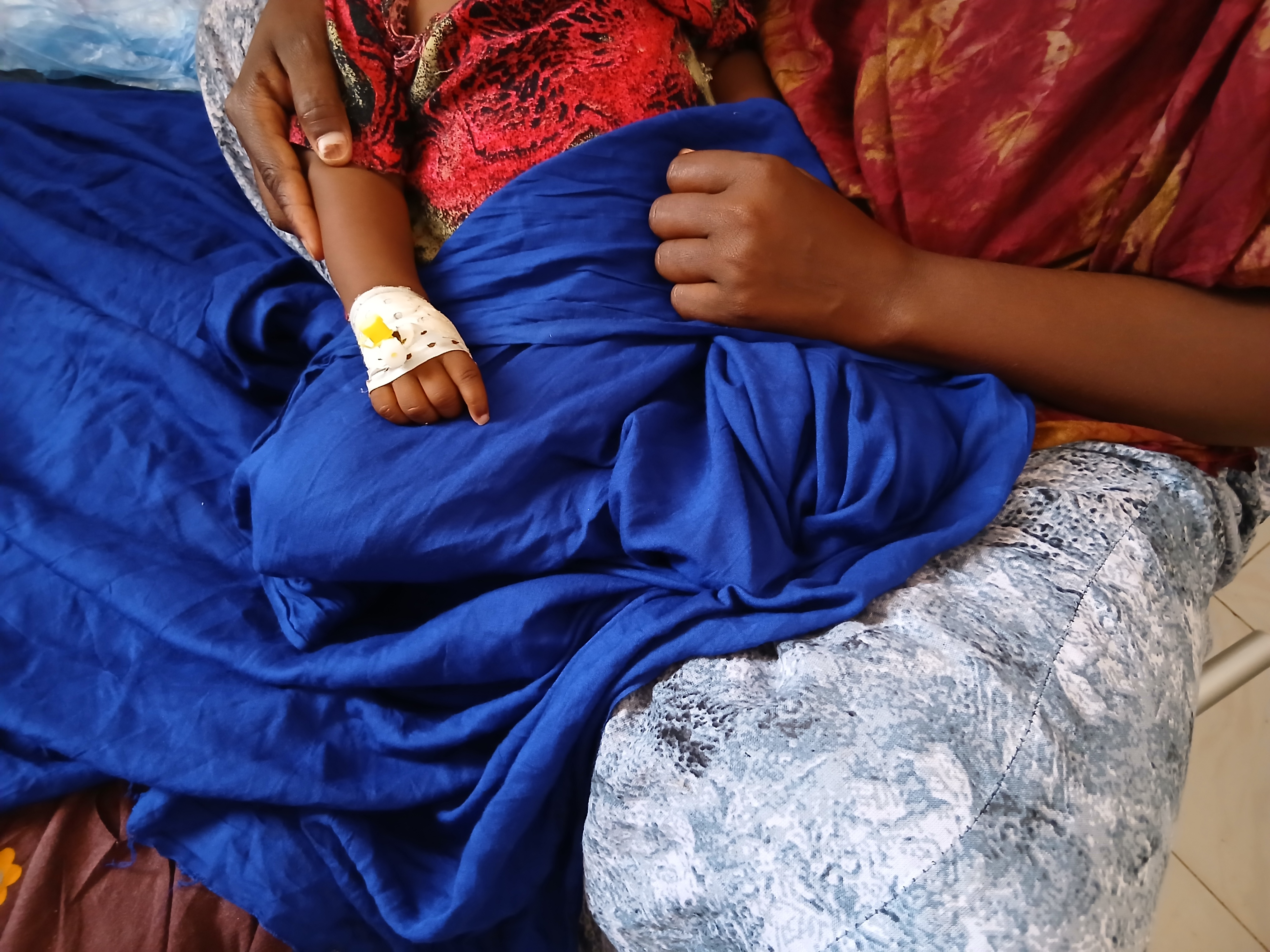 Een ouder houdt hun kind met mazelen vast