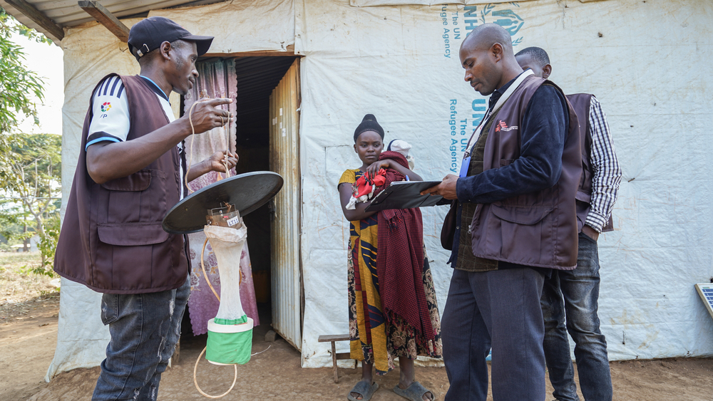 An MSF vector control unit member gathers information from a resident before setting up a mosquito trap inside her house in Nduta Camp.