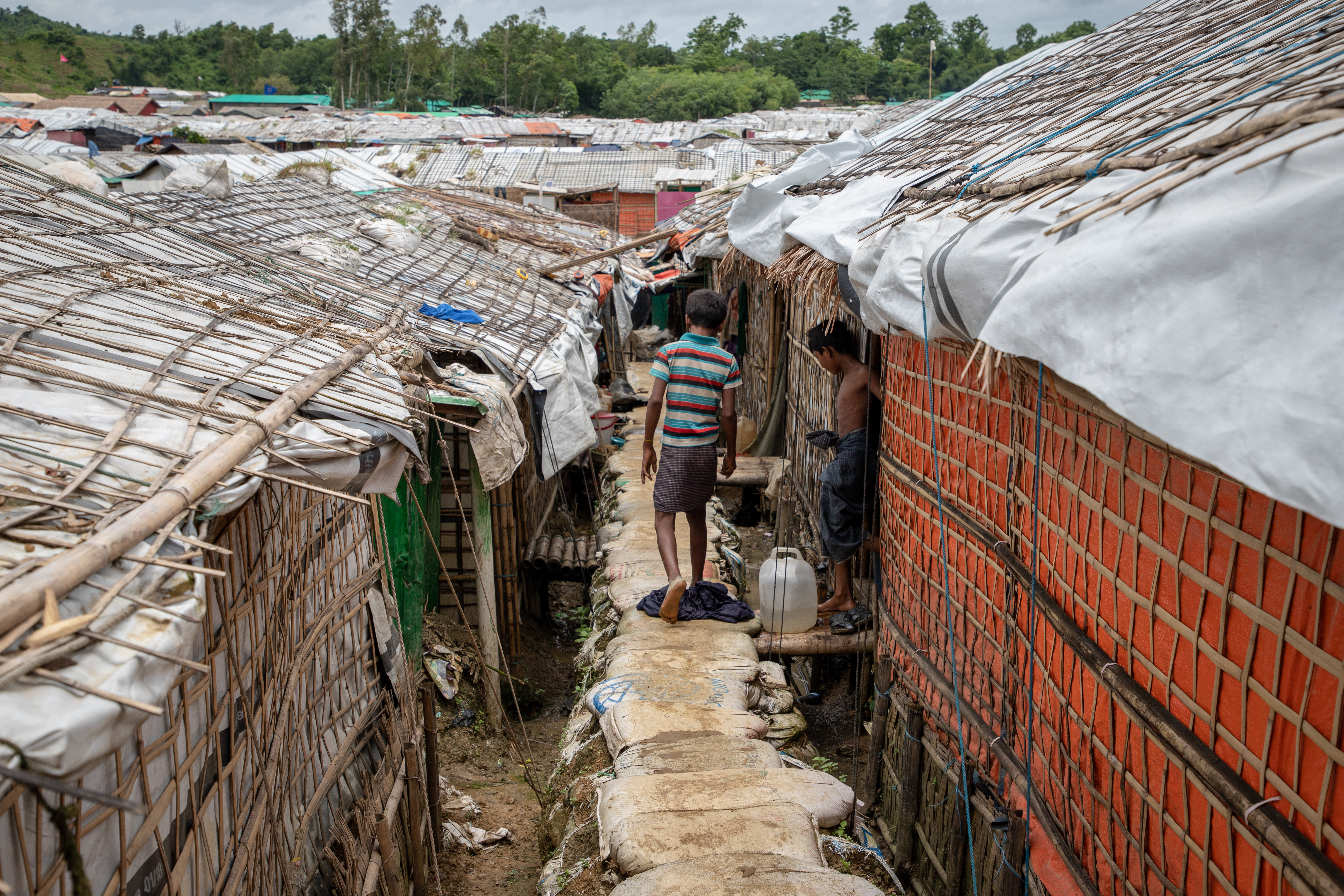 Un enfant marche sur un sentier surélevé renforcé par des sacs de sable dans le camp d’Unchiprang, à Cox’s Bazar, au Bangladesh. © Daphne Tolis, juillet 2018