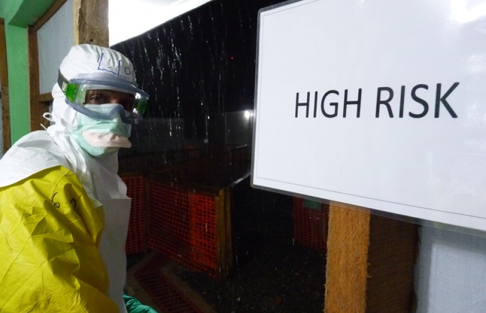 Un collaborateur en combinaison Ebola devant un centre de traitement