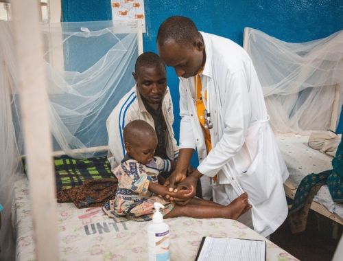 Lors de la visite médicale matinale, un médecin examine les œdèmes sur le corps d’Alice, une patiente admise pour malnutrition aiguë sévère au Centre de récupération nutritionnelle intensive de l’hôpital général de référence de Masisi
