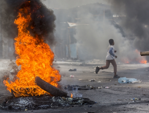 Un garçon court dans une rue bloquée par des pneus en feu lors d'une manifestation à Port-au-Prince le 13 juin 2019 © Jeanty Junio Augustin 